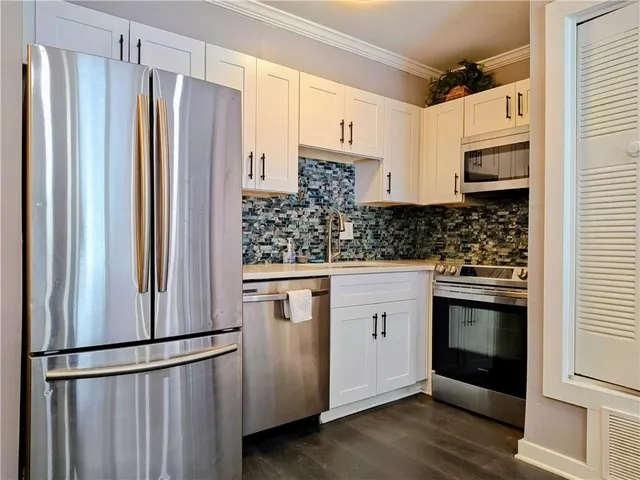 a kitchen with stainless steel appliances granite countertop a dining table chairs and a refrigerator