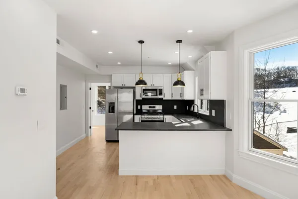 a kitchen with stainless steel appliances granite countertop a sink a stove a refrigerator and island with wooden floor