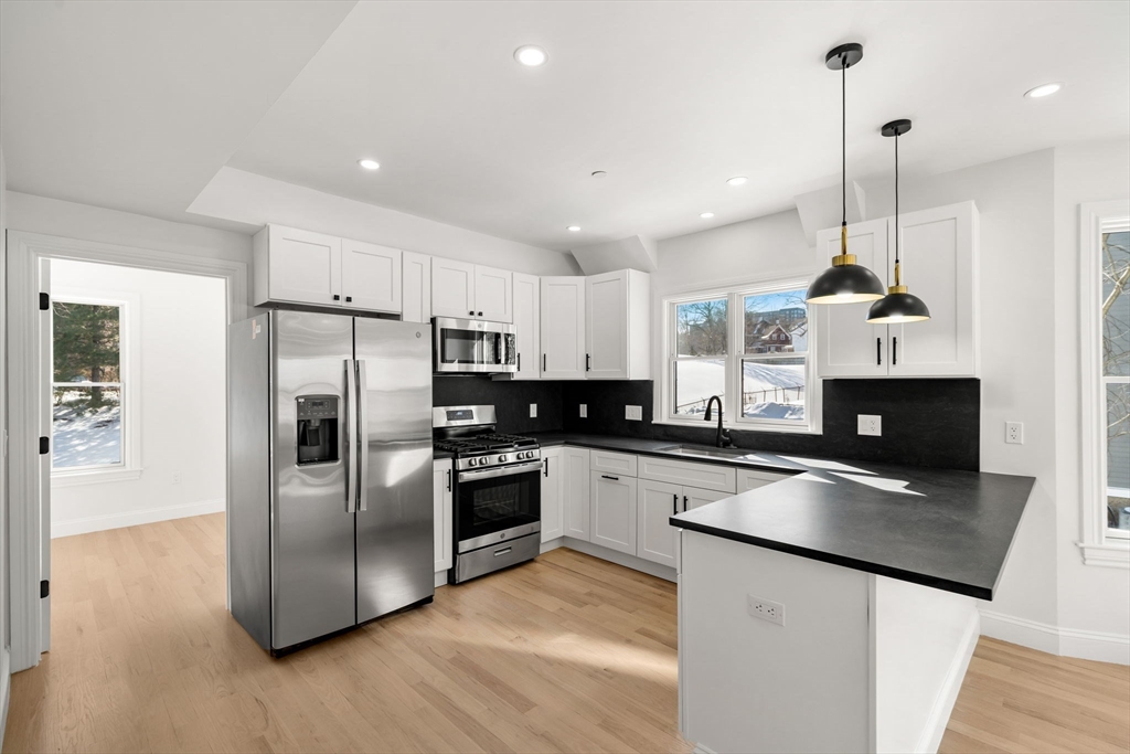 53 Dustin Street, Unit 2 Boston, MA 02135 - Photo 3 of 21 a kitchen with stainless steel appliances granite countertop a sink a stove a refrigerator and island with wooden floor