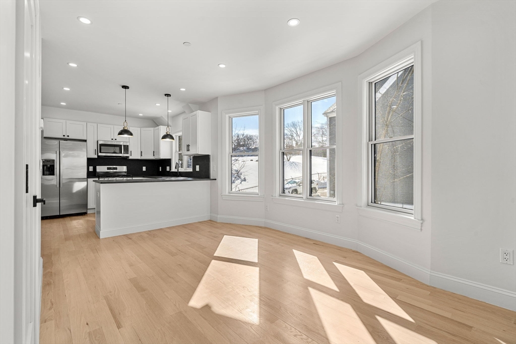 53 Dustin Street, Unit 2 Boston, MA 02135 - Photo 6 of 21 a large kitchen with stainless steel appliances kitchen island a large counter top and a wooden floor