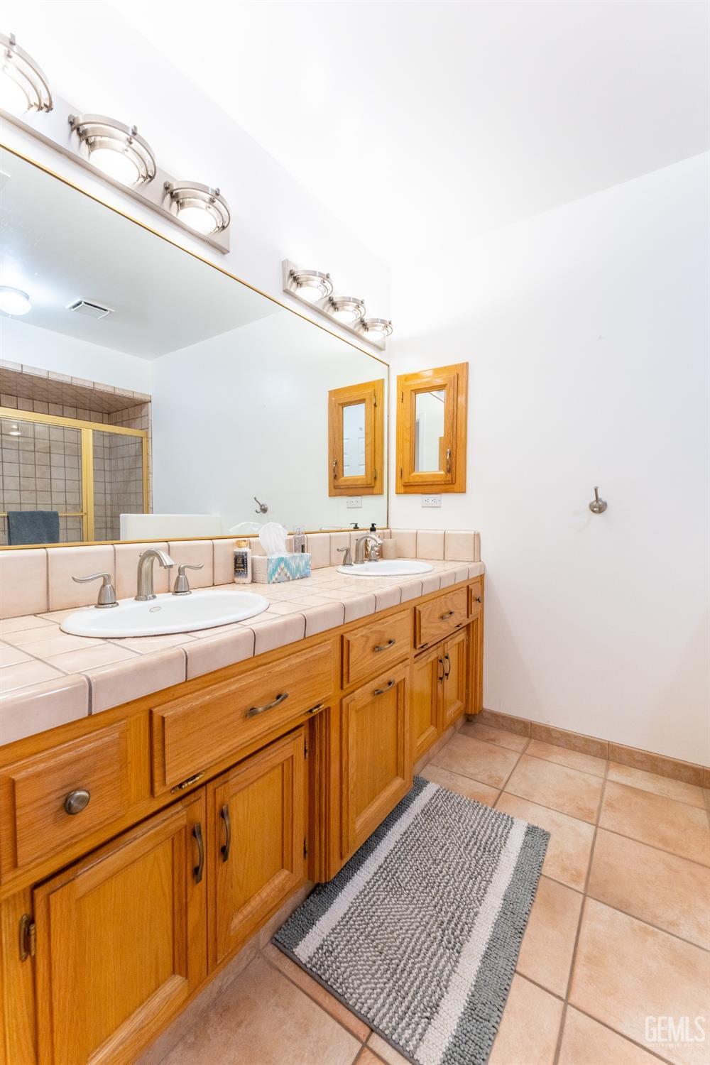 Undisclosed Address Bakersfield, CA 93314 - Photo 13 of 23 a spacious bathroom with a double vanity sink a mirror and a
