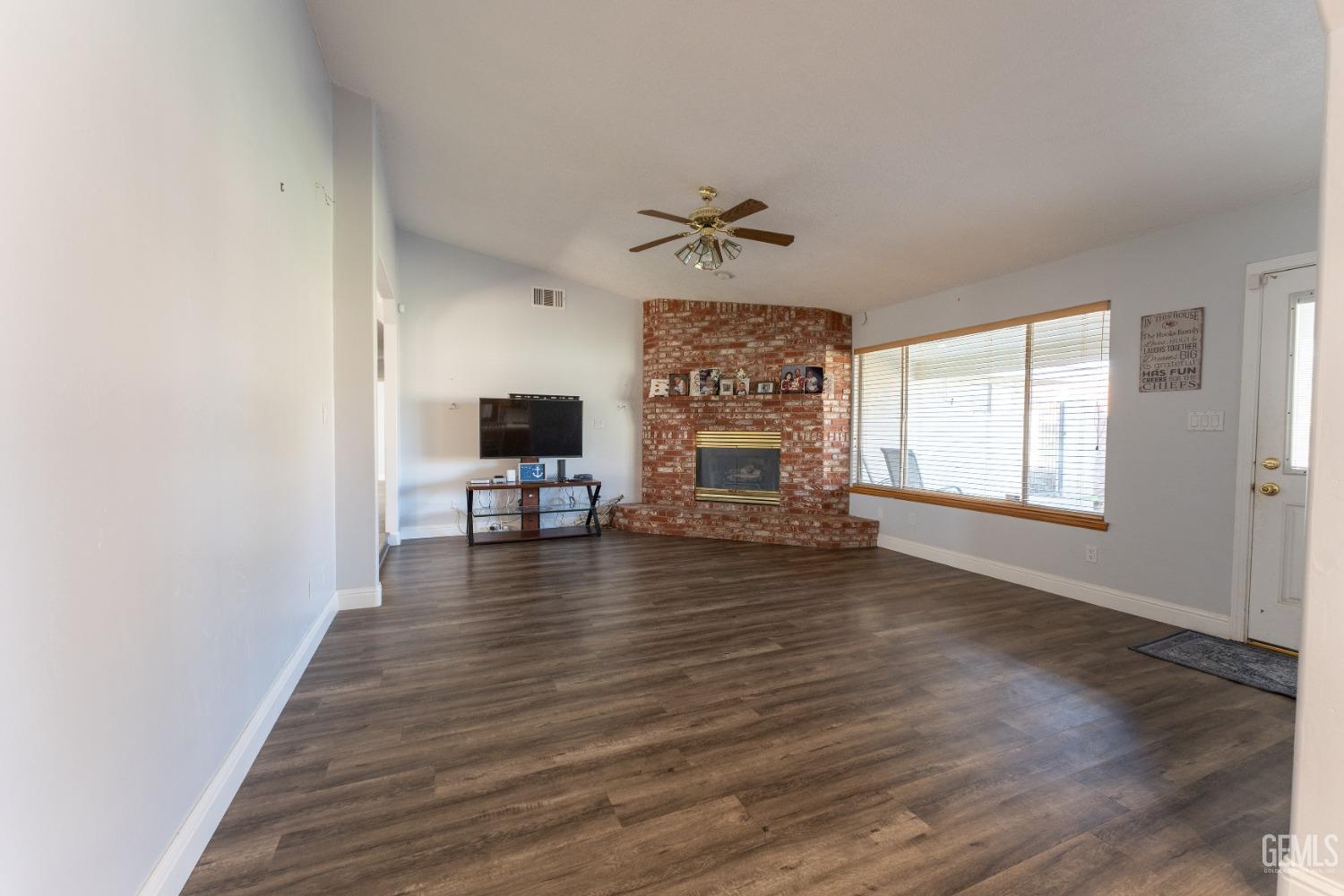 Undisclosed Address Bakersfield, CA 93314 - Photo 3 of 23 an empty room with wooden floor fireplace and windows