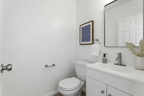 a bathroom with a toilet sink vanity and mirror