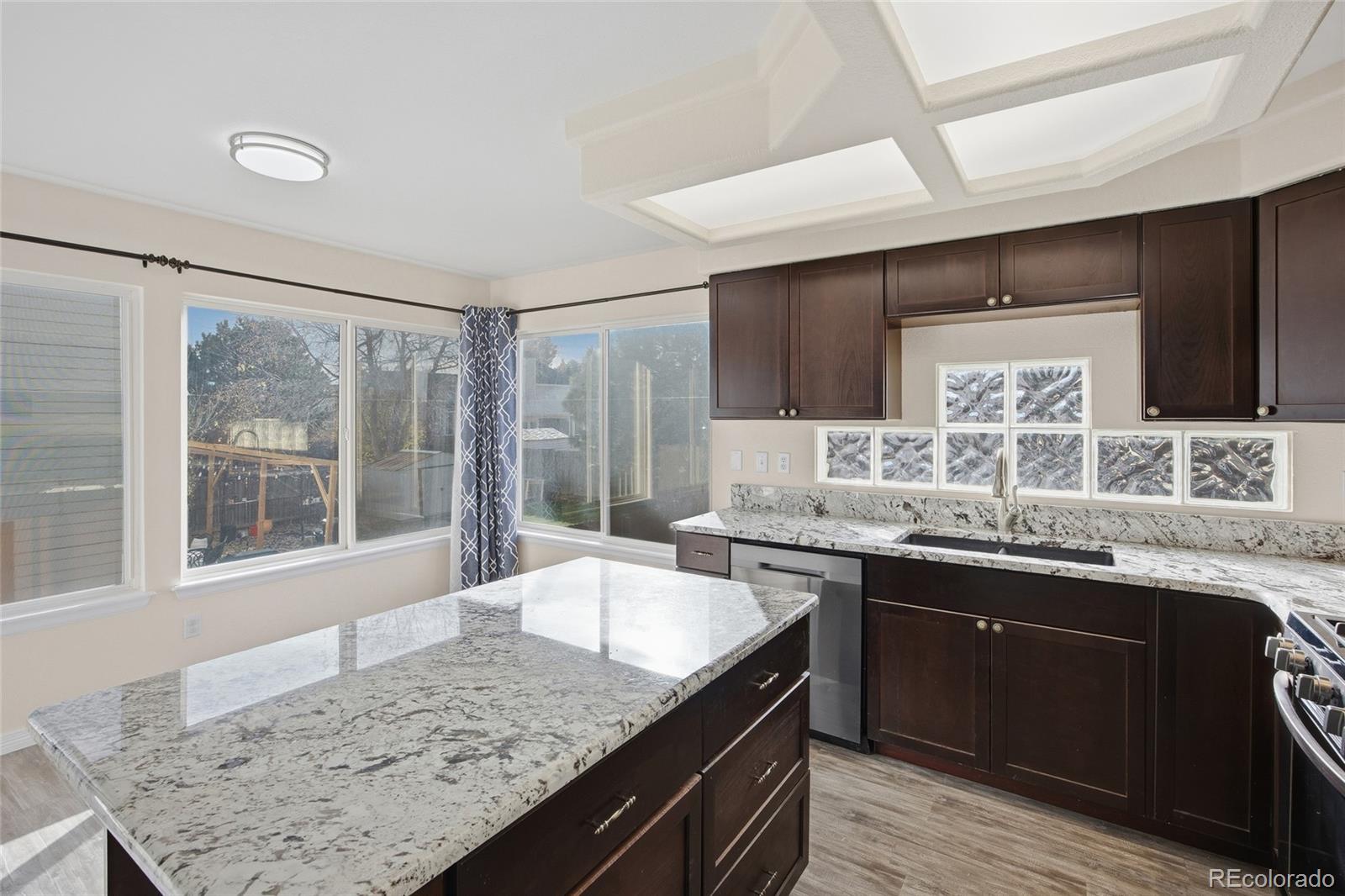 4531 Gibraltar Street Denver, CO 80249 - Photo 10 of 24 a kitchen with granite countertop sink stove and cabinets