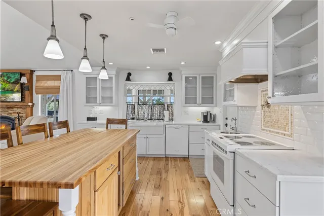 a kitchen with stainless steel appliances kitchen island granite countertop a stove a sink dishwasher and white cabinets with wooden floor