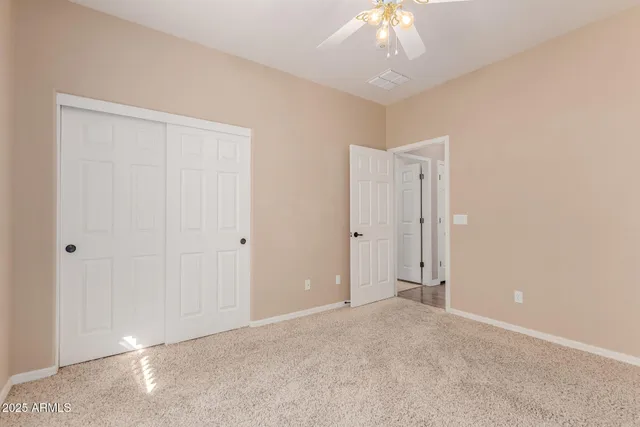 a view of an empty room and chandelier fan
