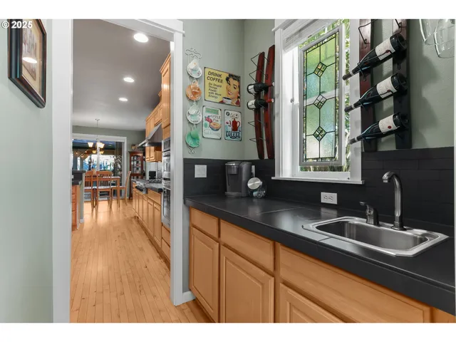 a kitchen with stainless steel appliances granite countertop a sink dishwasher a stove and a dining table with wooden floor