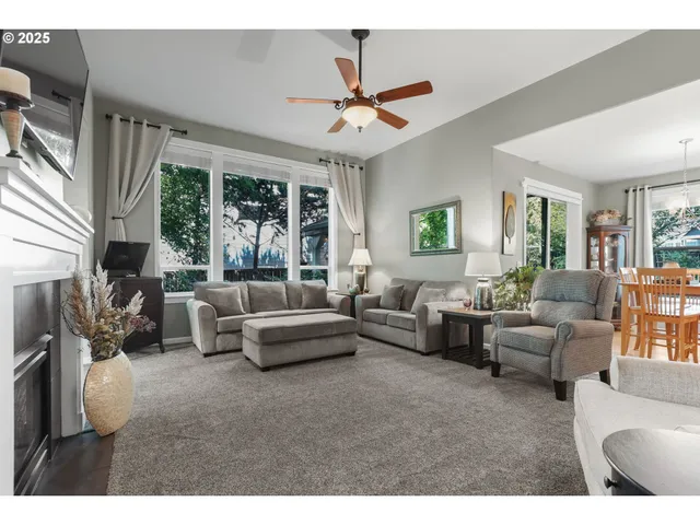a living room with furniture ceiling fan and a large window