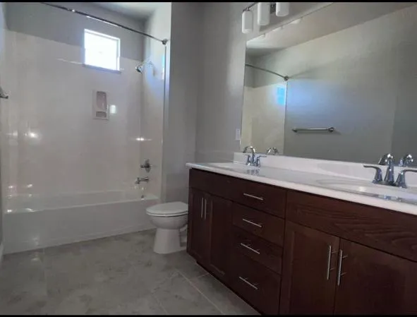a bathroom with a tub sink double vanity and toilet