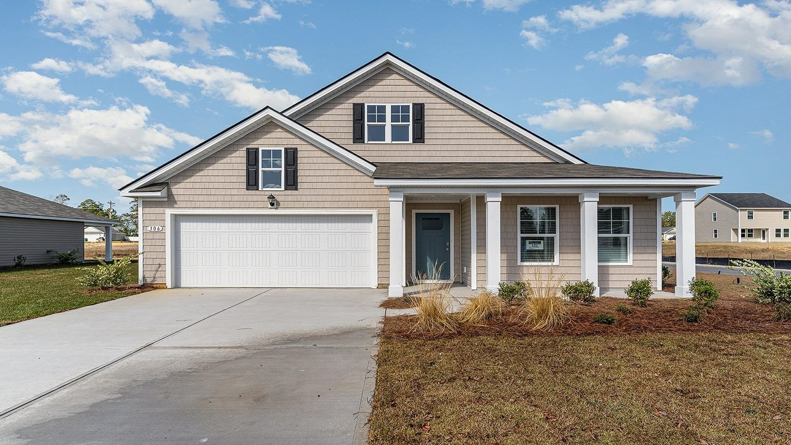 View of front of property featuring covered porch, driveway, and a front yard