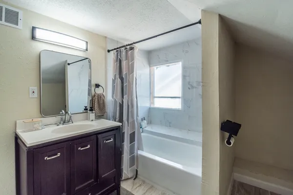 a bathroom with a bathtub shower sink vanity and mirror