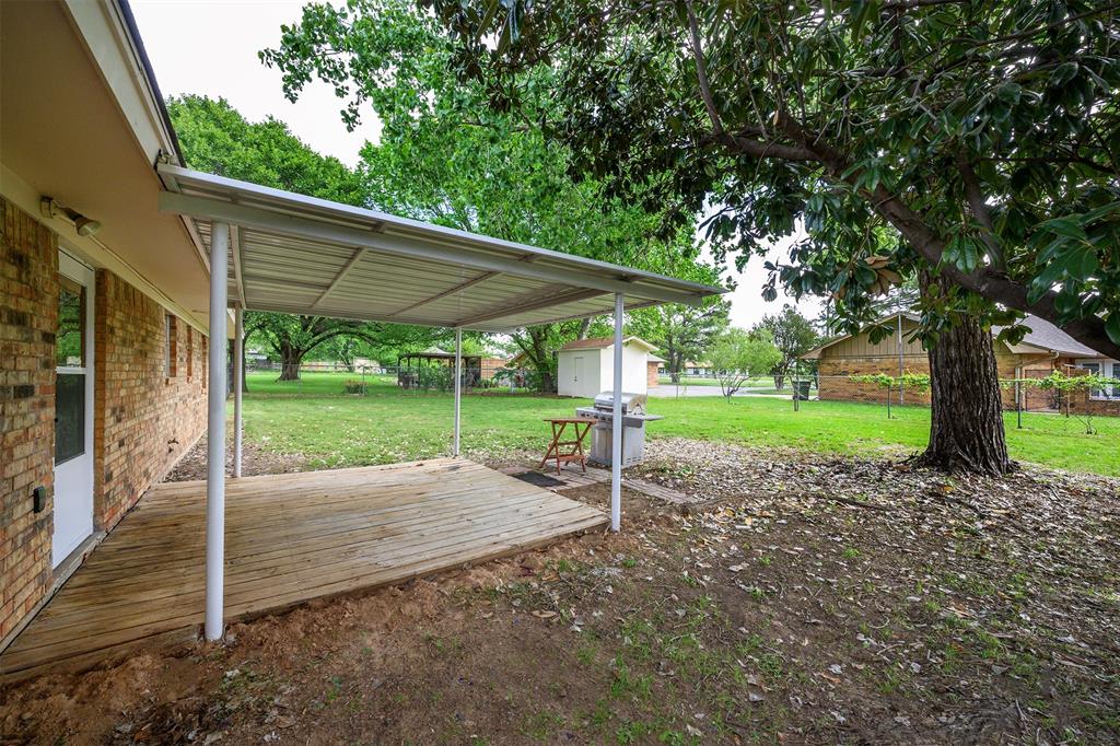 820 North Ave A Springtown, TX 76082 - Photo 21 of 27 Covered patio with wood-finish decking, offering direct access from the brick-clad exterior