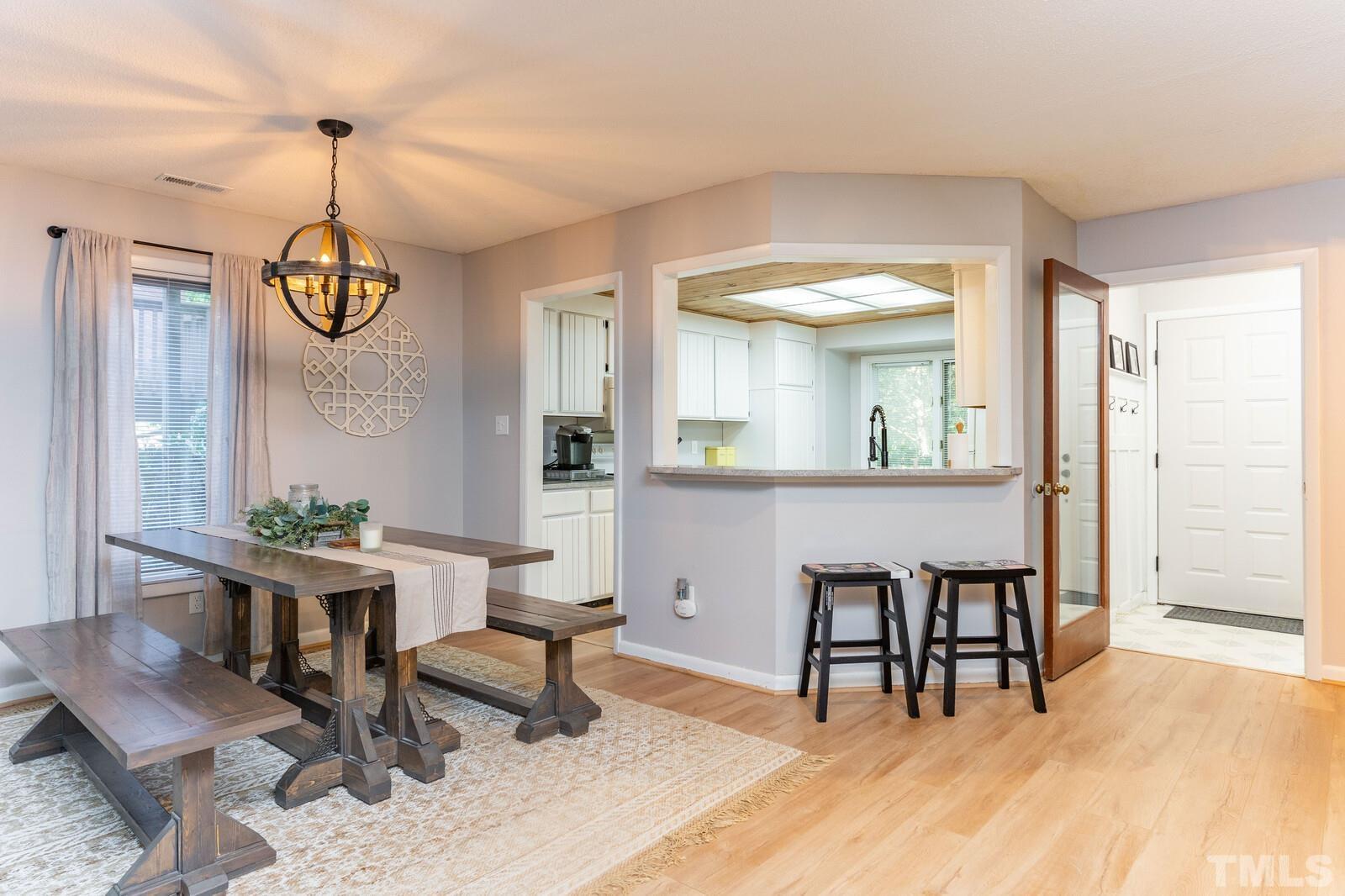 4353 Sunscape Lane Raleigh, NC 27613 - Photo 4 of 30 a dining room with furniture a chandelier and wooden floor
