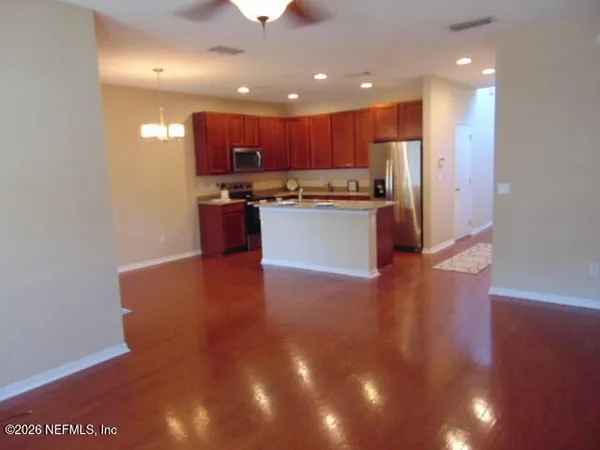 a large kitchen with stainless steel appliances granite countertop a large counter top a stove and a refrigerator with wooden floor