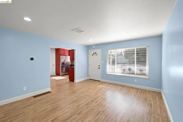 a view of an empty room with wooden floor and windows