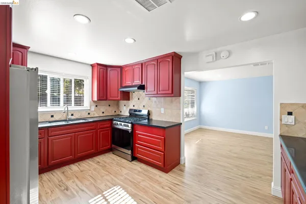 a kitchen with granite countertop a sink dishwasher stove and wooden cabinets