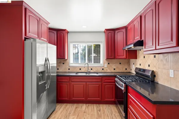 a kitchen with stainless steel appliances granite countertop a stove top oven a sink dishwasher and a refrigerator with wooden cabinets