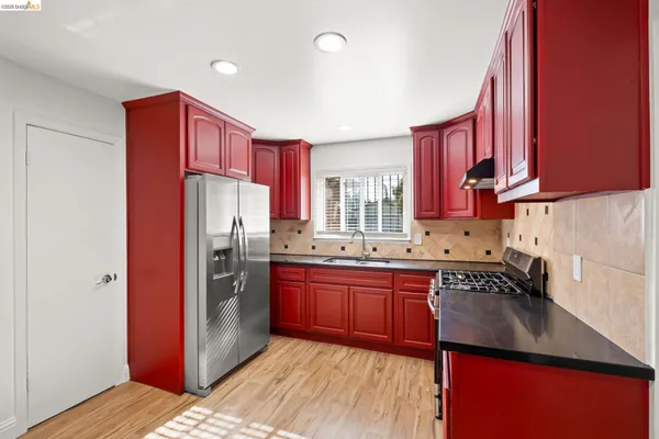 a kitchen with stainless steel appliances granite countertop a refrigerator a sink dishwasher a stove with wooden cabinets and floor