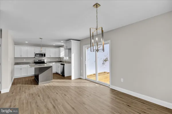 a open kitchen with a refrigerator a sink dishwasher a stove and white cabinets with wooden floor