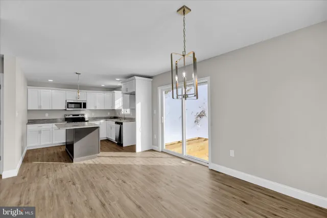 a open kitchen with a refrigerator a sink dishwasher a stove and white cabinets with wooden floor