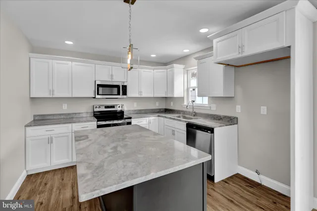 a kitchen with granite countertop a stove a sink and a refrigerator