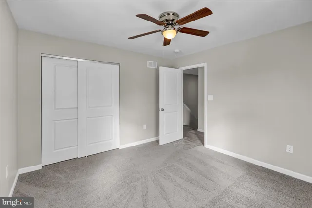 an empty room with closet and a ceiling fan