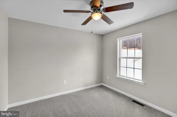 an empty room with closet and a ceiling fan