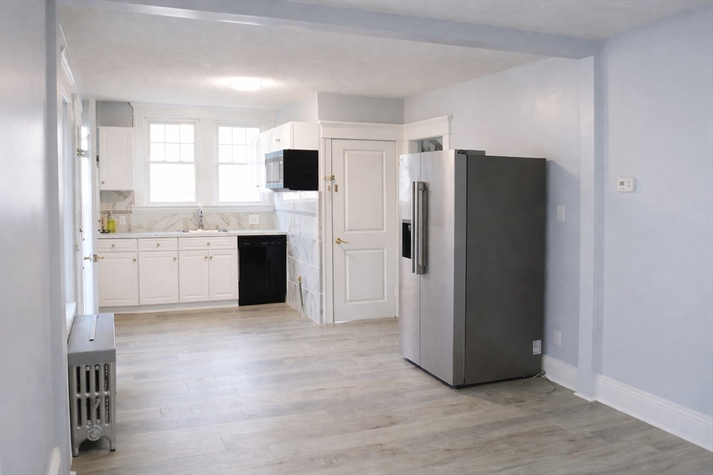 144 Washington Street Springfield, MA 01108 - Photo 3 of 18 a view of a kitchen with refrigerator and white cabinets