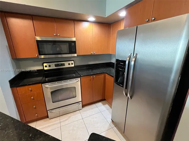 a kitchen with stainless steel appliances granite countertop a refrigerator a stove and a sink