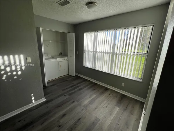 a view of an empty room with a window and wooden floor