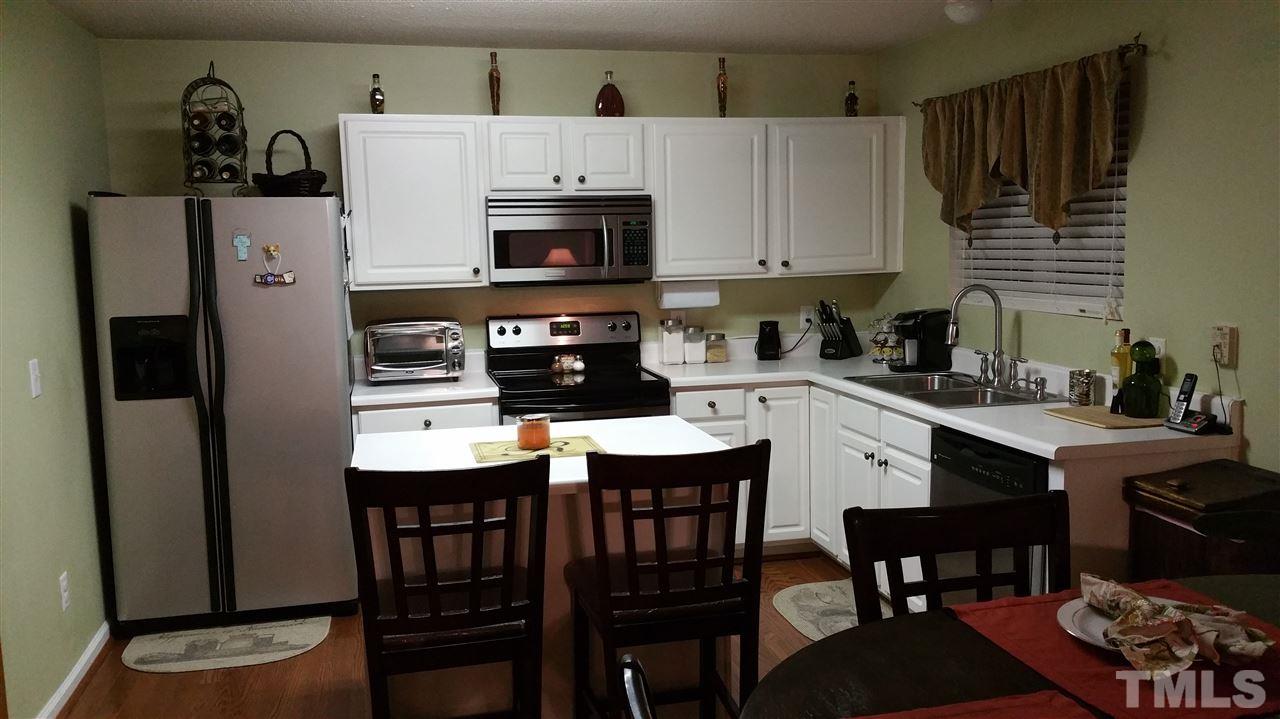 2901 Trassacks Drive Raleigh, NC 27610 - Photo 6 of 14 a kitchen with stainless steel appliances a dining table chairs microwave and sink