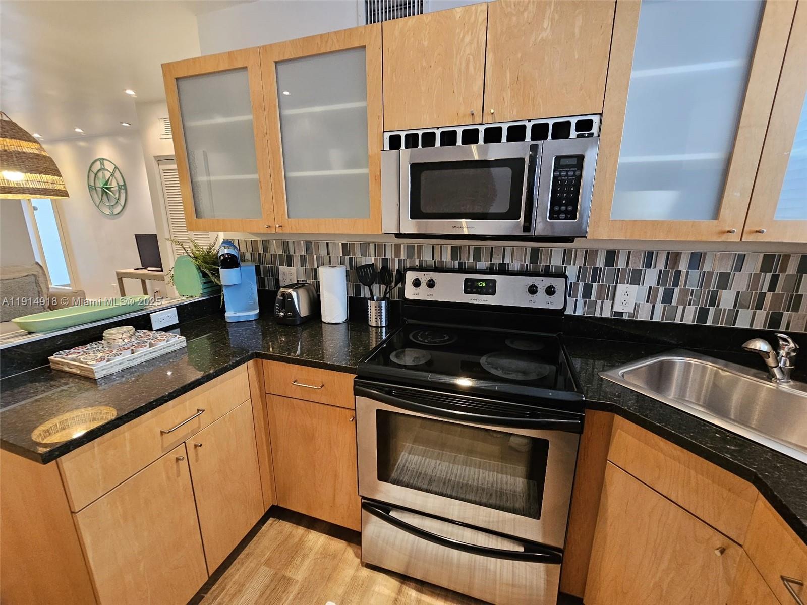 751 Collins Avenue, Unit 3 Miami Beach, FL 33139 - Photo 21 of 35 a kitchen with stainless steel appliances a stove a microwave a sink and cabinets