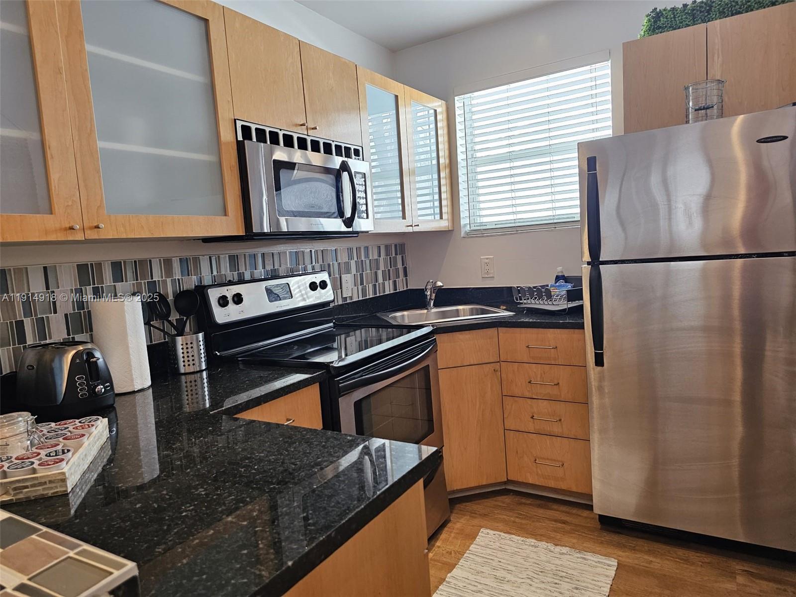 751 Collins Avenue, Unit 3 Miami Beach, FL 33139 - Photo 24 of 35 a kitchen with granite countertop a refrigerator a stove a sink and dishwasher