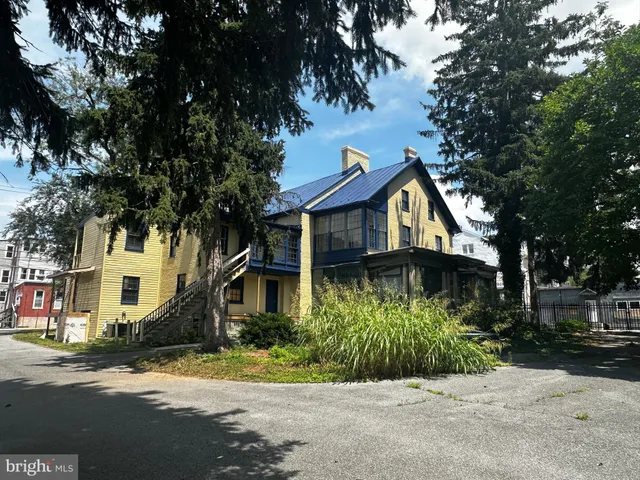 a front view of a house with a garden and tree