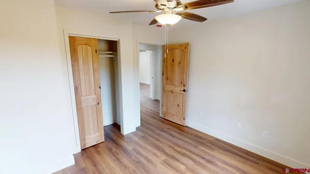 an empty room with wooden floor and a ceiling fan