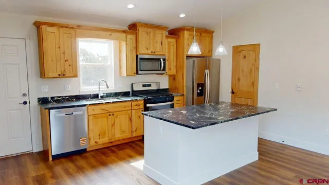 a kitchen with stainless steel appliances granite countertop a sink a stove and a wooden floor