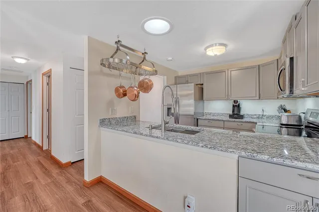 a kitchen with stainless steel appliances granite countertop a sink dishwasher and a refrigerator with wooden floor