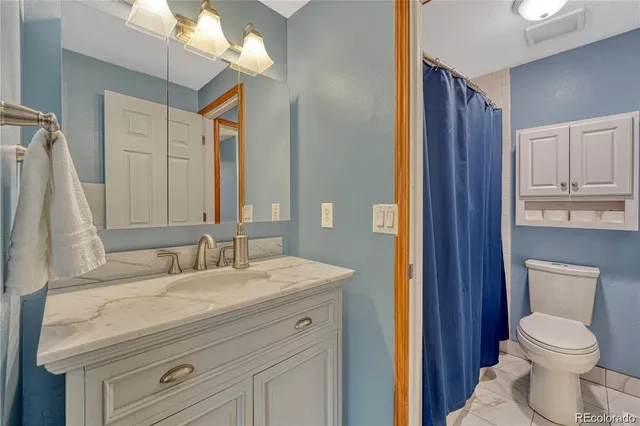 a bathroom with a granite countertop toilet sink and mirror