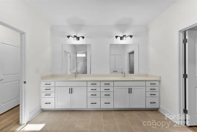 a spacious bathroom with a double vanity sink a mirror and a