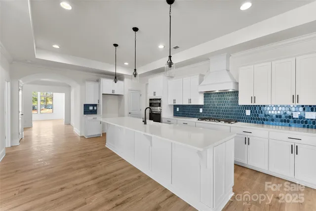 a large white kitchen with lots of counter space a sink appliances and cabinets
