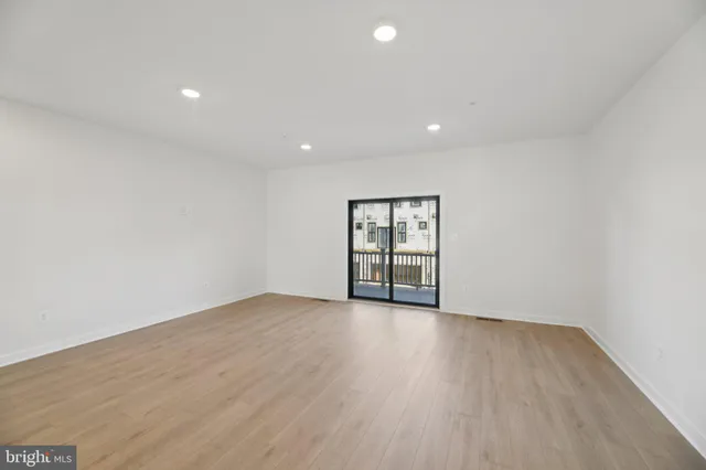 a view of an empty room with wooden floor and window
