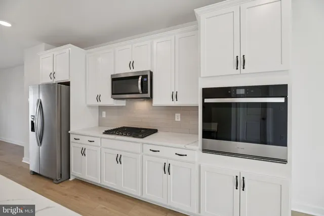 a kitchen with stainless steel appliances granite countertop white cabinets a refrigerator and a stove