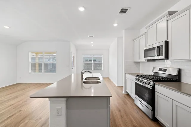 a kitchen with stainless steel appliances a stove sink microwave and cabinets