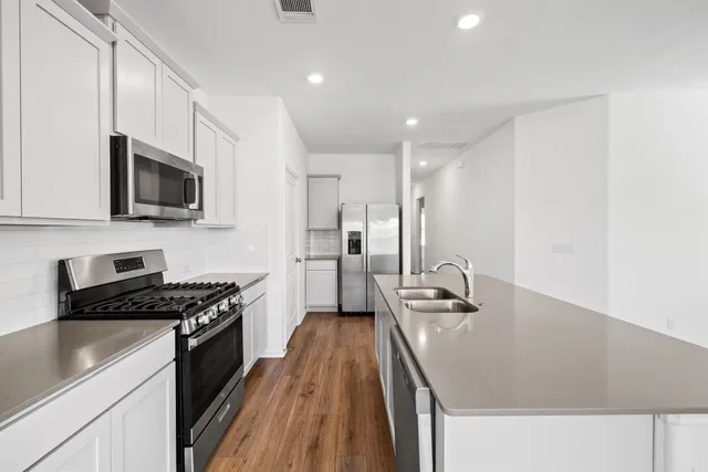 a kitchen with granite countertop a stove sink and refrigerator