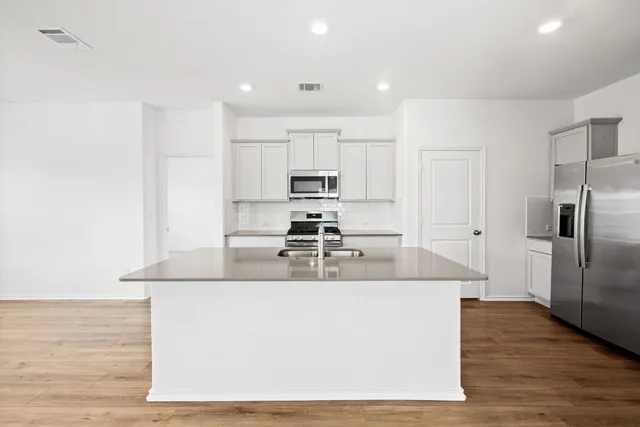 a large kitchen with kitchen island a large counter top and stainless steel appliances