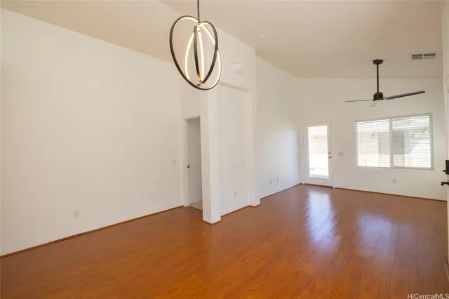 an empty room with wooden floor mirror and windows