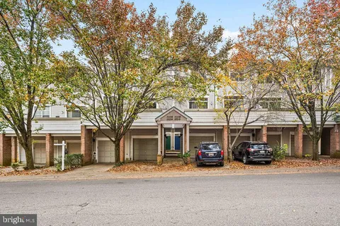 a front view of a building with lot of cars and trees