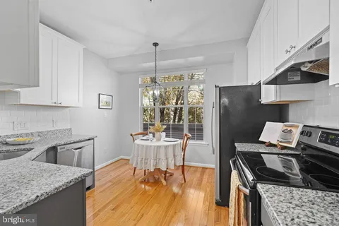 a kitchen with a stove a refrigerator and wooden floor