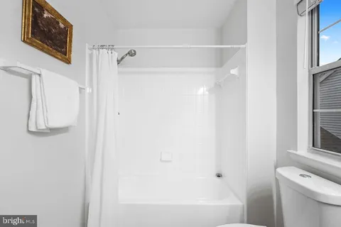 a bathroom with a toilet sink a mirror and a window