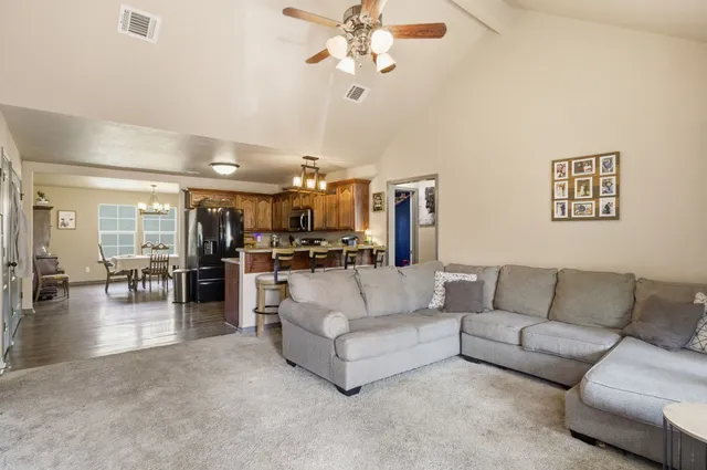 a living room with furniture kitchen view and a chandelier